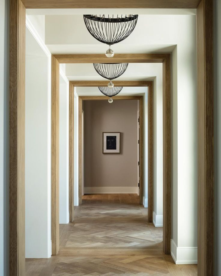 An image of a long hallway or living room where rhythm is clearly demonstrated. A series of identical black picture frames are hung along the wall, creating a strong sense of repetition. The pattern in the runner rug also leads the eye down the hall, demonstrating transition.
